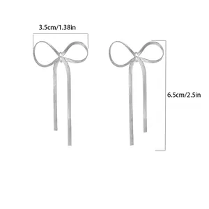 Detail view of 18K gold bow tassel earrings showing 3.5cm width and 6.5cm length