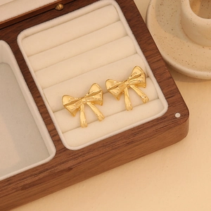 Close-up of gold bow earrings with polished metal finish in a velvet jewelry box