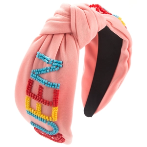 Détail d'un serre-tête rose noué avec broderie LOVE en perles colorées et tissu en coton