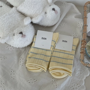 Detail of yellow cotton socks with blue stripes and wavy cuffs on white fabric