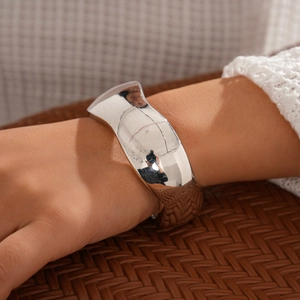 Polished silver wide open cuff bracelet in minimalist industrial style worn on a wrist