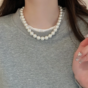 Close-up of minimalist pearl necklace worn on neck for a chic French-style aesthetic