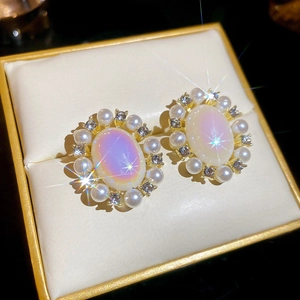 Detailed macro view of vintage oval earrings with iridescent stone and pearls in a box