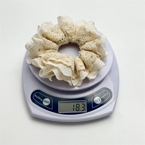Lace ruffle scrunchie in beige hollow floral design weighed on a digital scale