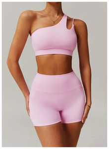 Detail of light pink one-shoulder asymmetric yoga sports bra and high-waisted gym shorts