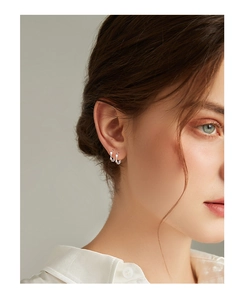 Close-up of minimalist S999 silver Mobius hoop earrings worn by a model for a stylish look