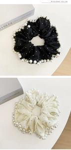 Détail de grands chouchous en tulle brodé noir et blanc avec perles et strass brillants