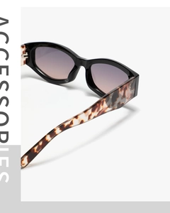 Detail shot of black cat-eye sunglasses featuring tortoiseshell temples and gradient lenses