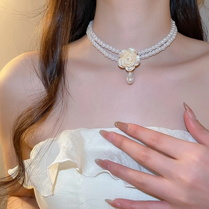 Gros plan d'un collier de perles double rang avec fleur de camélia et pendentif goutte
