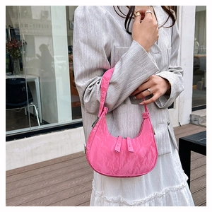 Detail of pink wrinkled patent leather crescent bag worn with a chic street style outfit