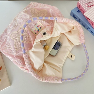 Detail der rosa Spitzentasche mit Schmetterlingsstickerei und geflochtenen Griffen