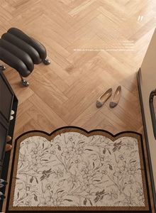 Detail of vintage floral PVC entryway rug with elegant scalloped black edges on wood floor