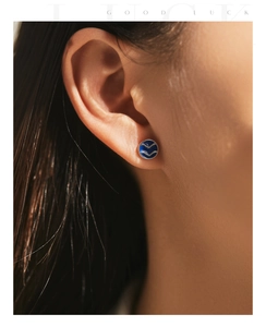 Gros plan d'une boucle d'oreille tulipe en argent s925 et émail bleu sur le lobe