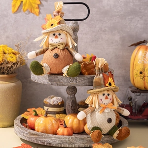 Macro detail of Thanksgiving scarecrow dolls on a rustic tiered tray with autumn maple leaves
