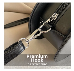 Close-up of premium silver metal hook and stitching on black pebbled leather crossbody bag