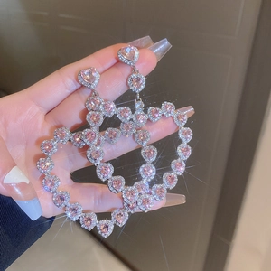 Close-up of heart earrings with pink rhinestones and a sparkling starburst effect