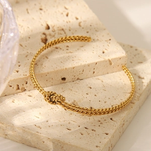 Detailansicht eines goldenen geometrischen Knotendesign-Armreifs auf Steinoberfläche