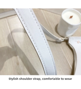 Detail shot of white leather shoulder strap featuring precise stitching and smooth texture