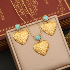 Gold-tone heart necklace and earrings set with turquoise stones on leather jewelry box