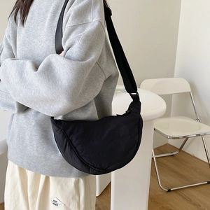 Detail of minimalist black nylon crescent bag with adjustable wide shoulder strap on model