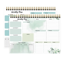 Close-up of weekly planner layout with green watercolor leaves and spiral binding