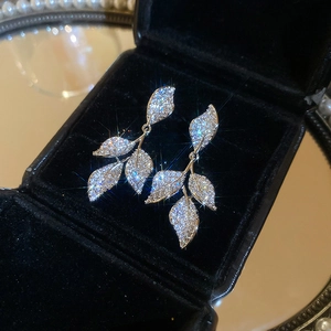 Detailed close-up of silver leaf drop earrings with sparkling pavé zircons on black velvet