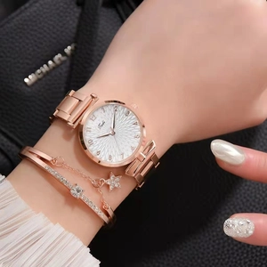 Close-up of rose gold watch and star pendant bracelet set on a black textured bag