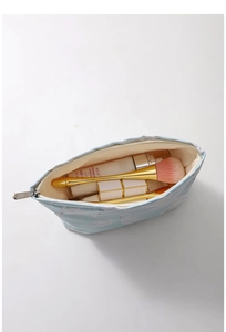 Internal view of a light blue canvas makeup bag with white swan patterns and zipper