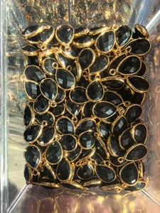 Bulk black teardrop crystal pendants with faceted surfaces and golden metal frames