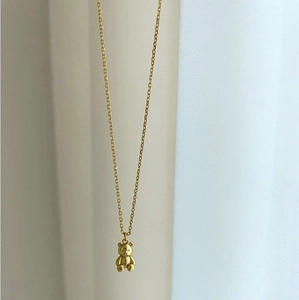 Close-up of a 925 sterling silver golden teddy bear pendant on a minimalist necklace chain