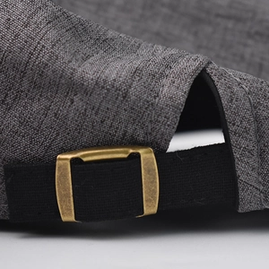 Detail of adjustable metal buckle and textured grey cotton fabric on the beret cap