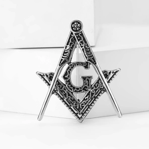 Macro shot of vintage silver Masonic brooch featuring G symbol and relief texture