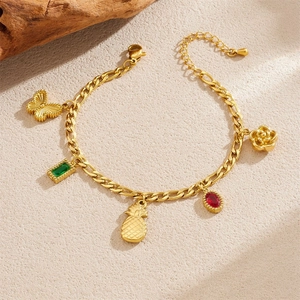 Detailed view of a gold-plated bracelet with butterfly and gemstone fruit charms