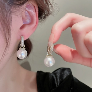 Close-up of elegant gold-plated pearl drop earrings with sparkling zircon inlay detail