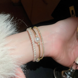 Close-up of pearl beads and gold bangle set with sparkling rhinestones on model wrist