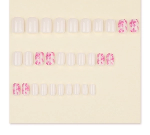 Flat lay of milky white square-round nails with pink flower patterns on a cream background