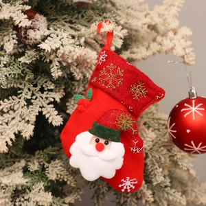Detail of red Christmas stocking with Santa Claus doll hanging on a snowy tree branch