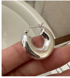Gros plan sur une boucle d'oreille créole en argent massif S925 poli en forme de C