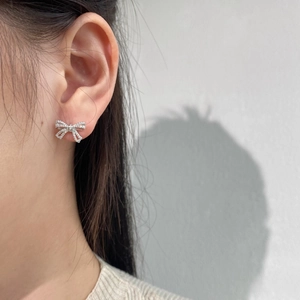 S925 silver bow stud earrings with sparkling diamonds on female model ear close-up