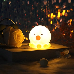 Close-up of a glowing octopus night light emitting warm yellow light on a book