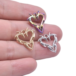 Three heart-shaped dragon pendants in gold, silver, and rainbow colors held on fingertips