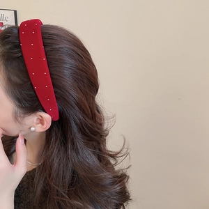 Close-up of vintage red velvet headband with white pearls and elegant padded design