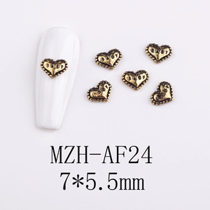 Macro detail of vintage gold alloy heart nail charms with BABY engraving and relief texture