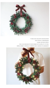Detail of Christmas wreath featuring red berries, pine cones, and warm glowing LED lights