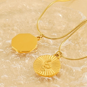 Macro detail of gold snake chain with octagonal mirror and snake coin relief pendants