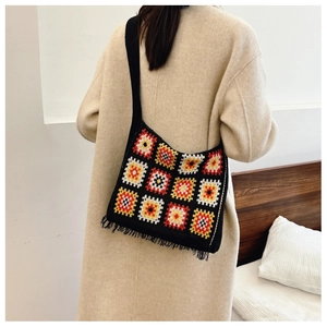 Detail of crochet tote bag with colorful granny squares and black fringe on beige coat