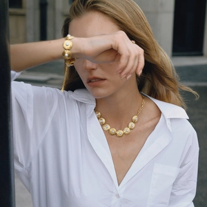 Close-up of elegant 18K gold-plated necklace and bracelet set with pearls on a model