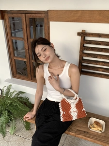 Detail of hand-woven crochet handbag in orange and cream colors for bohemian summer style
