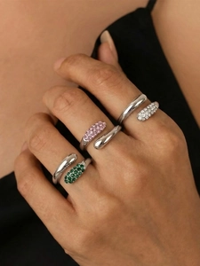 Macro view of bypass teardrop rings with green, pink, and white zircon settings