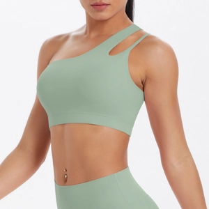 Detail of sage green one-shoulder sports bra featuring asymmetric cutout shoulder straps